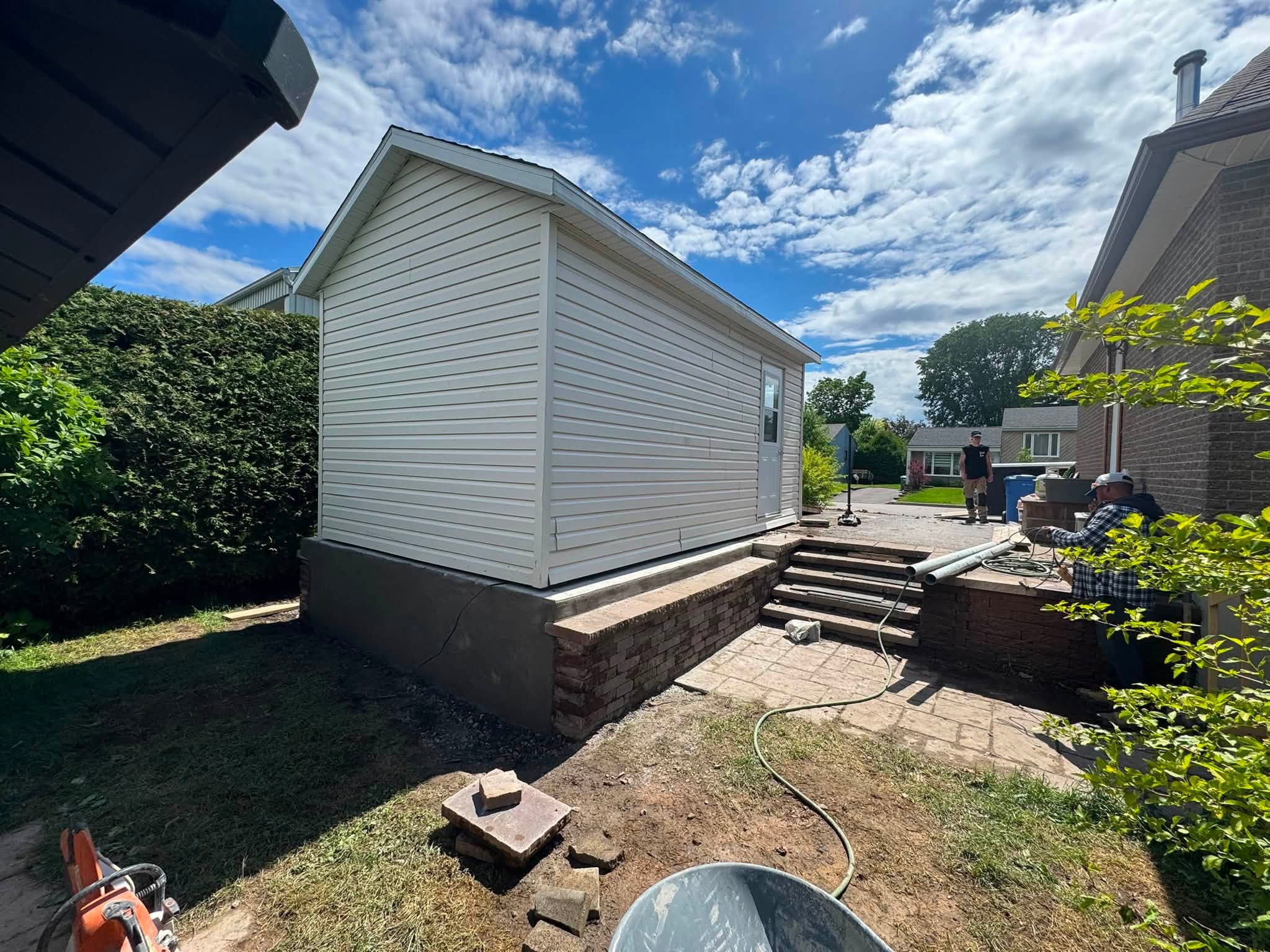 Agrandissement de stationnement et base de garage en béton à Québec — cabanon posé sur sa nouvelle base, muret et marches terminés