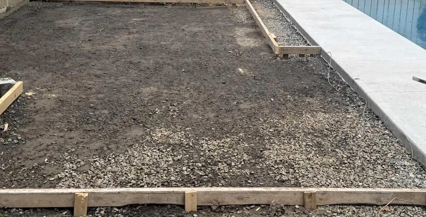 Coffrage de bois et base de pierre concassée compactée avant le coulage d'une dalle, chantier Terrassement Primo